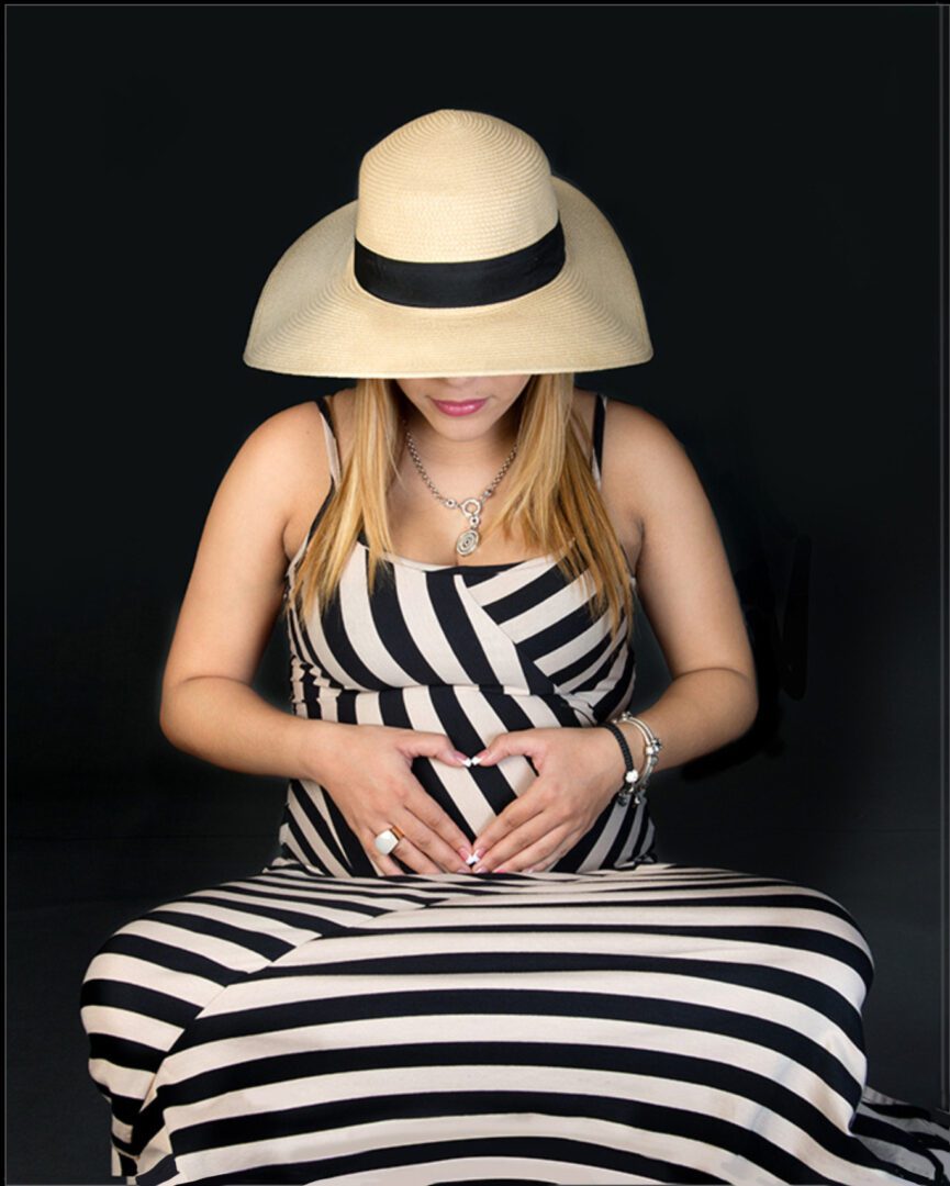 Pregnant woman wearing a hat and striped dress.